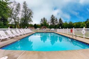 a swimming pool with white chairs and a fence at Charming and casual motel in a great location with shared resort amenities in Lincoln +19 photos