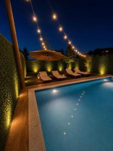 a swimming pool with chairs and an umbrella at night at Wooden Villa Eilin 2 in Tirana