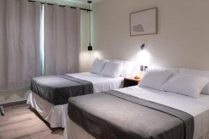 a hotel room with two beds and a window at Hotel Casa Arbórea in San José
