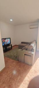 a living room with a couch and a flat screen tv at 2 Bedrooms Apulia Front Beach Flat in Apúlia