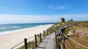 a wooden path leading to a beach with a lighthouse at 2 Bedrooms Apulia Front Beach Flat in Apúlia