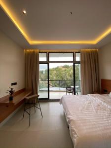 a bedroom with a bed and a desk and a large window at الدغيثر للشقق المخدومه in Ash Shafa