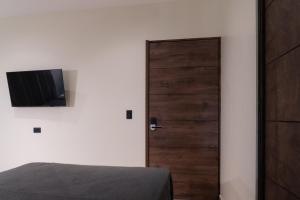 a bedroom with a bed and a door with a television at Hotel Casa Arbórea in San José