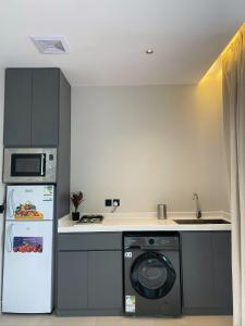 a small kitchen with a refrigerator and a washer at الدغيثر للشقق المخدومه in Ash Shafa
