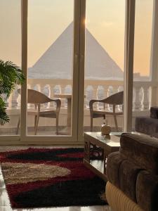 a living room with a view of a pyramid seen through windows at Hi Pyramids in Cairo