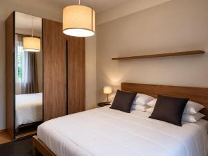 a bedroom with a large white bed and a mirror at Casa Vacanza Saint George - Hotel San Giuseppe Group in Cernobbio +2 photos