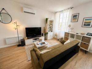 a living room with a couch and a tv at Les Cœurs de Ribérac - Hyper centre - Climatisation - Wi-Fi in Ribérac