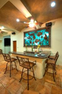 a kitchen with a bar with chairs and a painting on the wall at Las Palmas Oceanfront Villas and Casitas in Santa Cruz Huatulco