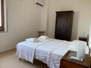 a bedroom with a white bed and a wooden cabinet at Terrazzo Vista Mare Mozzafiato in Cariati