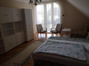 a bedroom with a bed and two chairs and a table at Kossuth Apartman in Hajdúszoboszló