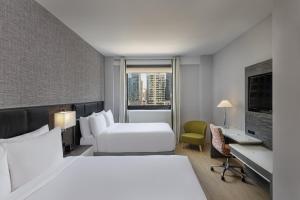 a hotel room with two beds and a desk at Four Points by Sheraton Manhattan Midtown West in New York