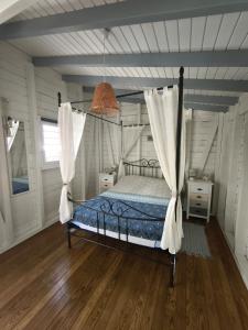 a bedroom with a canopy bed with curtains and wooden floors at Villa Rosa Karibella in Saint-François +50 photos