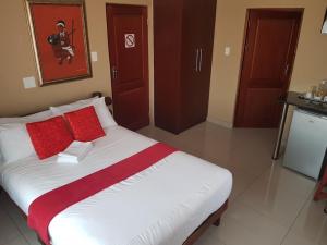 a bedroom with a large bed with red pillows at Moonlight Guesthouse in Bloemfontein