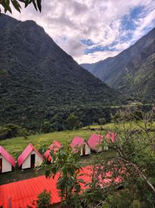 a group of red houses in a valley with mountains at Refugio Salkantay collpapampa in Colcapampa