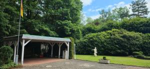 a pavilion with a statue in a garden with a flag at Villa Albert in Euskirchen