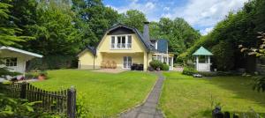 a yellow house with a fence and a yard at Villa Albert in Euskirchen