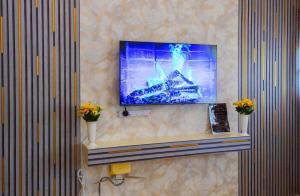 a flat screen tv on a wall with two vases at Cherve BnB in Nakuru