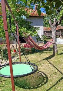 a hammock in a yard with a tree at Dragačevska kuća na bregu- Heritage House in Viča