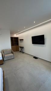 a living room with a couch and a television on a wall at ALAR Rooms in Dhërmi +14 photos