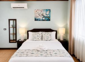 a bedroom with a large bed with two lamps at Hotel Espadilla Gardens in Quepos