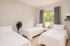two beds in a white room with a window at Quinta do Sol Condominium - Pirenópolis in Pirenópolis