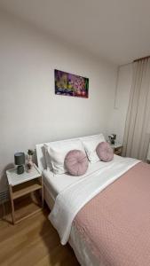 a bedroom with a bed with pink pillows on it at The Nook Apartment in Jesenice