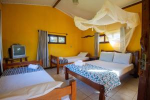 a bedroom with two beds and a tv at Pousada Casa da Trilha in Vale do Capao