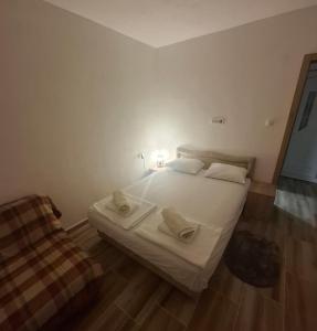 a bedroom with a white bed and a chair at Nido Apartman in Kotor