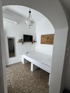 a white room with a bed and a tv at Nostalgia Traditional Home in Skiros