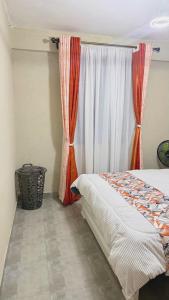 a bedroom with a bed and a window with curtains at Kaizen Homes in Homa Bay +5 photos