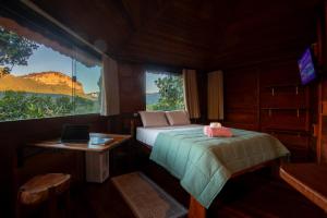 a bedroom with a bed and a desk and a window at Pousada Casa da Trilha in Vale do Capao