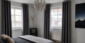 a bedroom with two windows and a chandelier at Acorn Hill Apartments in Nidda