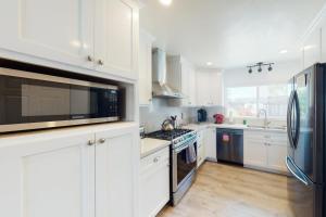 a kitchen with white cabinets and a black refrigerator at Portola Oasis - Permit DRO-STR-18 in Monterey