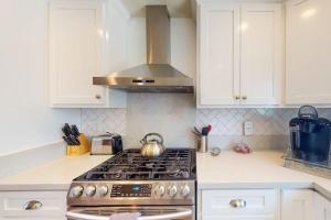 a stove top oven in a kitchen with white cabinets at Portola Oasis - Permit DRO-STR-18 in Monterey +16 photos