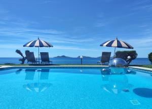a swimming pool with umbrellas and chairs and the ocean at LÚA Cies Room in Oya