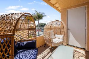 a balcony with two wicker chairs and two swings at Santo Tomas Getaway in Grover Beach