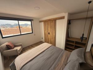 a bedroom with a bed and a chair and a window at Suite Vlady in Cuenca