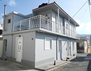 a white building with a balcony on top of it at George's Stonehouse in Samos