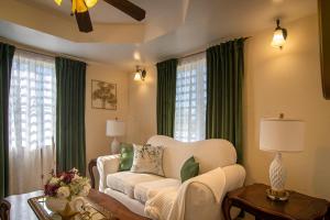 a living room with a white couch and green curtains at Carmich Place in Saint Johnʼs