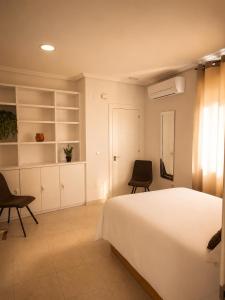 a bedroom with a white bed and two chairs at Apartamentos Joli in Olivares de Duero