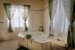 a bathroom with a tub and a toilet and a window at Carmich Place in Saint Johnʼs +34 photos