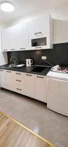 a kitchen with white cabinets and a black counter top at Rose 2 Apartment in Jajce
