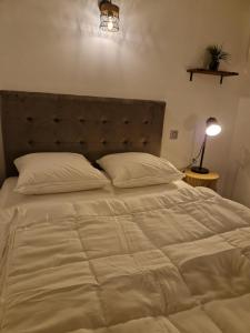 a large white bed in a bedroom with a lamp at Maisonnette à 350m de la plage in Berck-sur-Mer