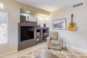 a living room with a tv and a chair and a guitar at Vistoso Resort Casita #163 in Oro Valley