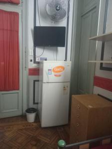 a small refrigerator in a room with a television at Tinta Roja Residencia Estudiantil in Buenos Aires