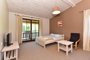 a bedroom with a bed and a tv and a balcony at Luokesų Dvaro sodyba in Ažuluokesa