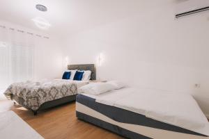 two beds in a bedroom with white walls and wood floors at Dëshira Apartments in Ulcinj