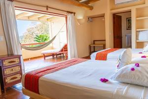 two beds in a room with a large window at Hotel Catalina Beach Resort in Zihuatanejo