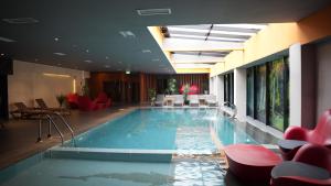 a swimming pool in a hotel with red chairs at Palace Hotel & SPA in Mitrovica