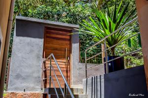 dom z drewnianymi drzwiami i schodami w obiekcie Jardim Secreto w mieście Morro de São Paulo